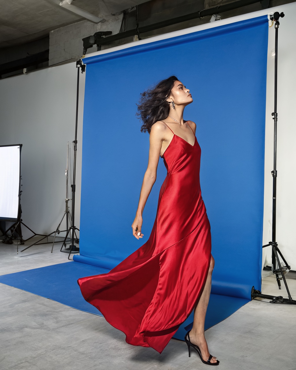 Real model in a crimson silk dress on a blue chroma-key screen in a photo studio