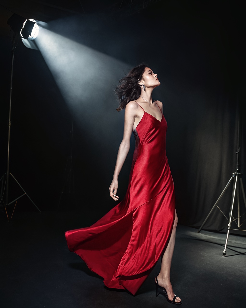 Same model and dress in a dark studio under a single spotlight